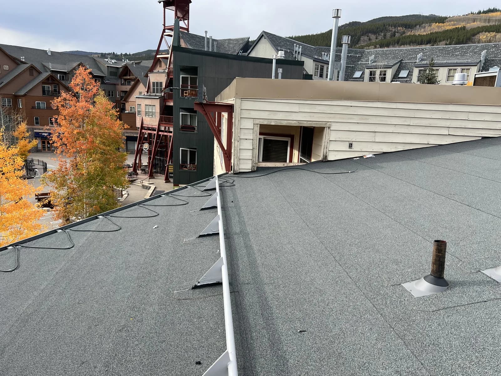 Low-slope roof surface with penetrations and adjoining roof areas