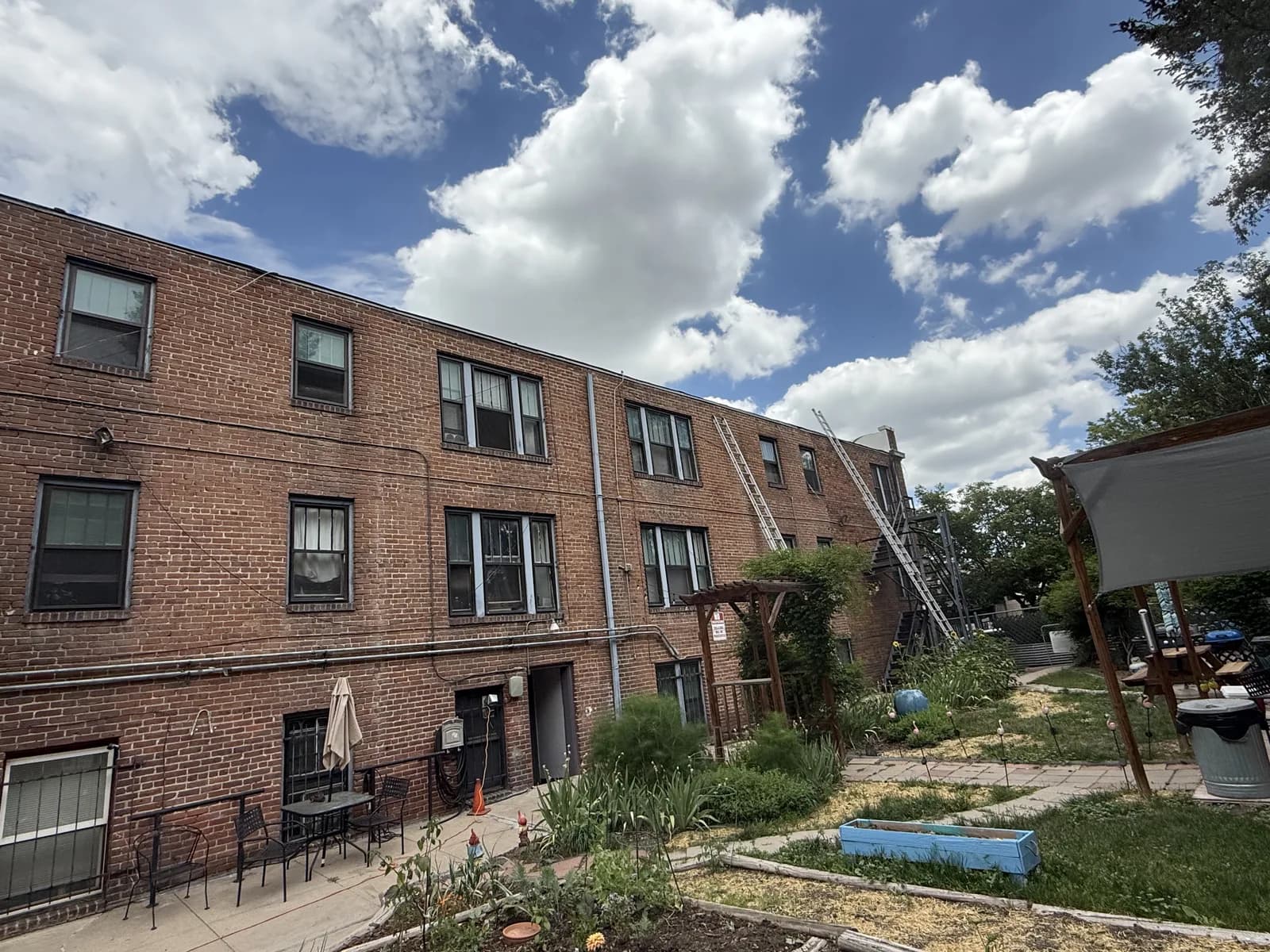 A brick building exterior with windows, downspouts and access ladders
