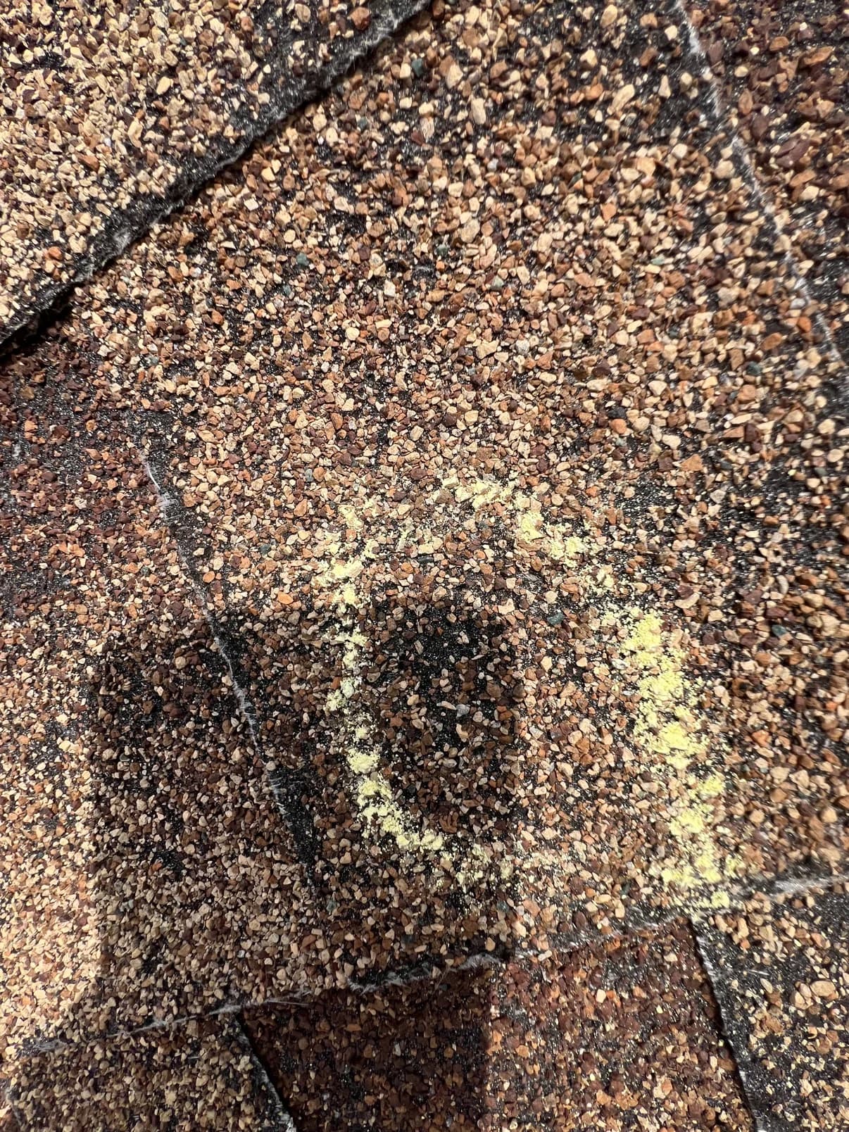 Close view of granular shingles with a chalk-circled area