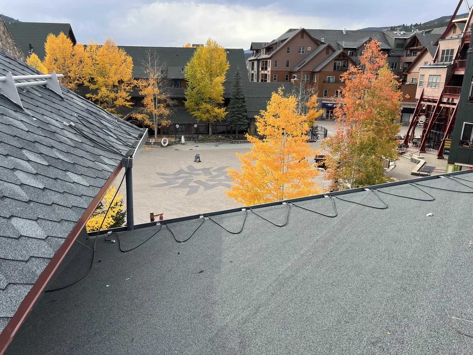 A granular low-slope roof beside an adjoining pitched roof and exterior wall