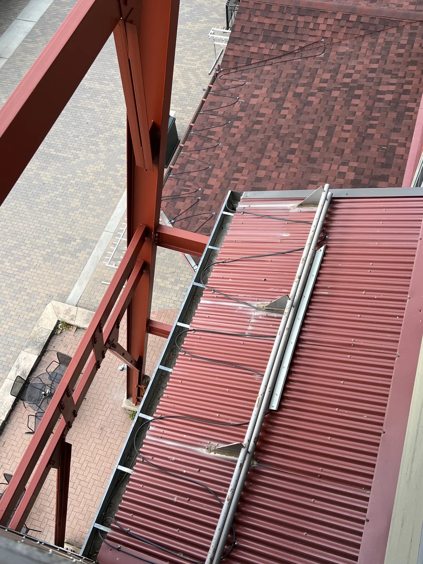Red metal roof panels, a gutter and roof-mounted cables seen from above