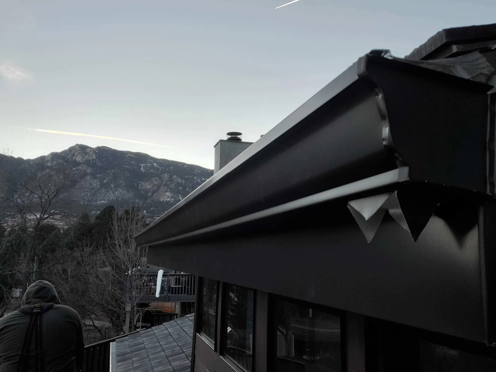 Black seamless gutter install detail on a Highlands Ranch home with Front Range mountain view
